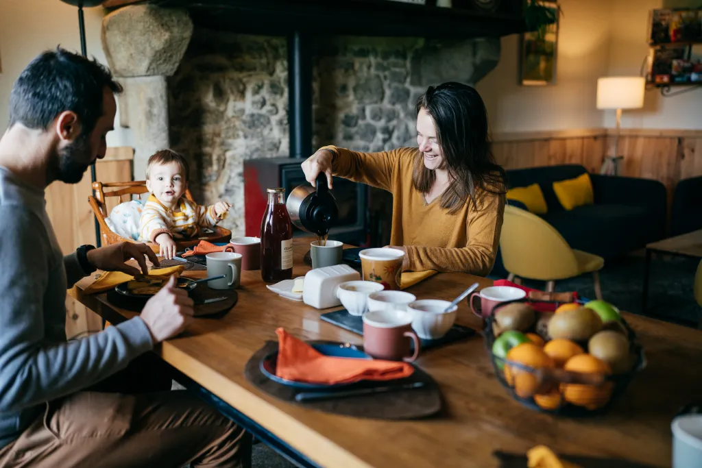 Famille au petit-déjeuner devant la cheminée du gîte