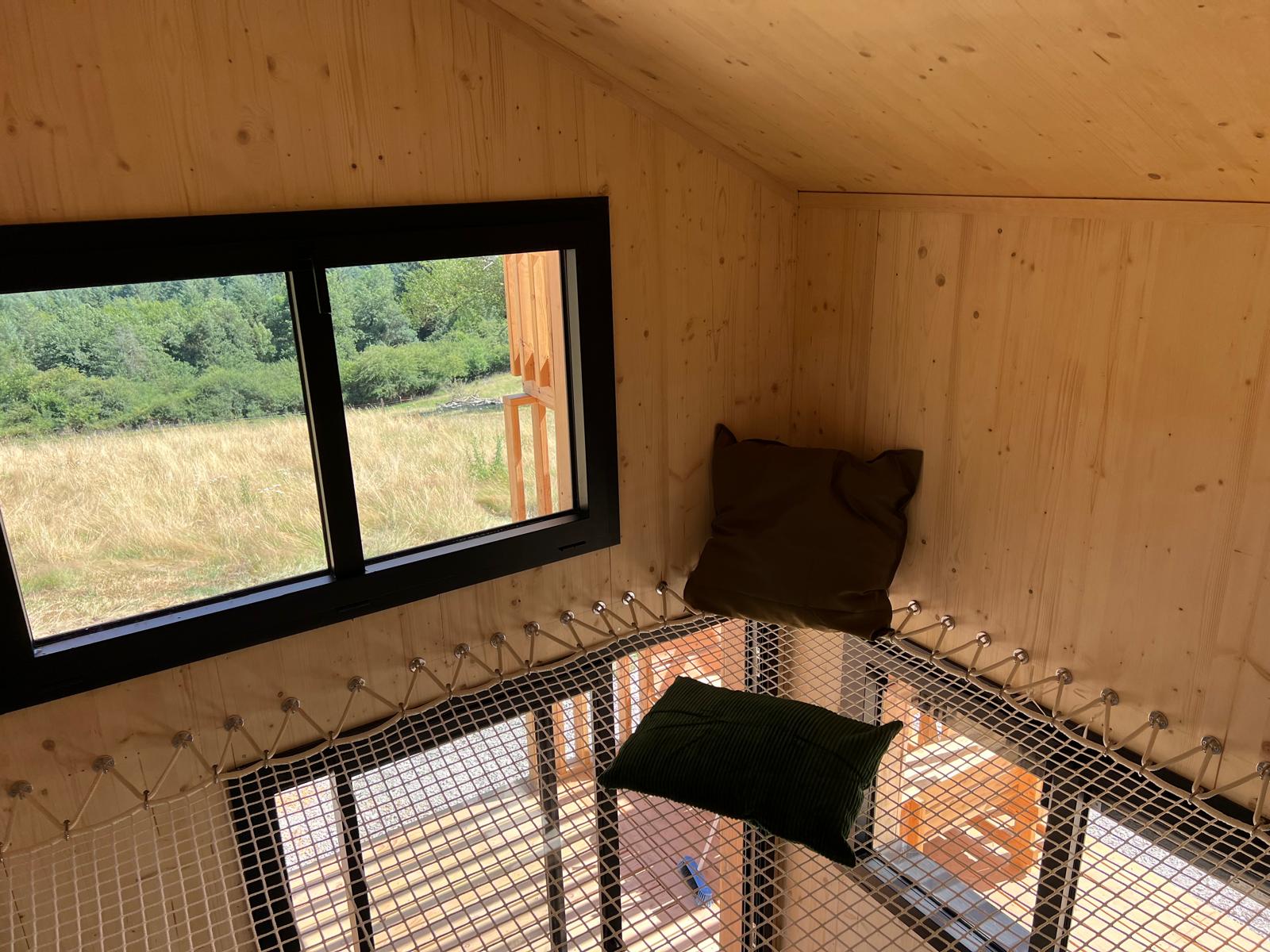 Mezzanine du COQhome avec filet suspendu et vue sur la prairie