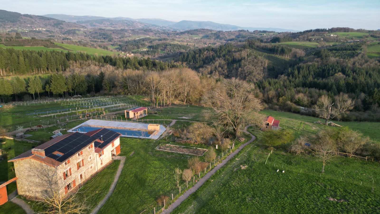 Vue aérienne du domaine avec le gîte, le bassin de nage et les collines du Livradois-Forez