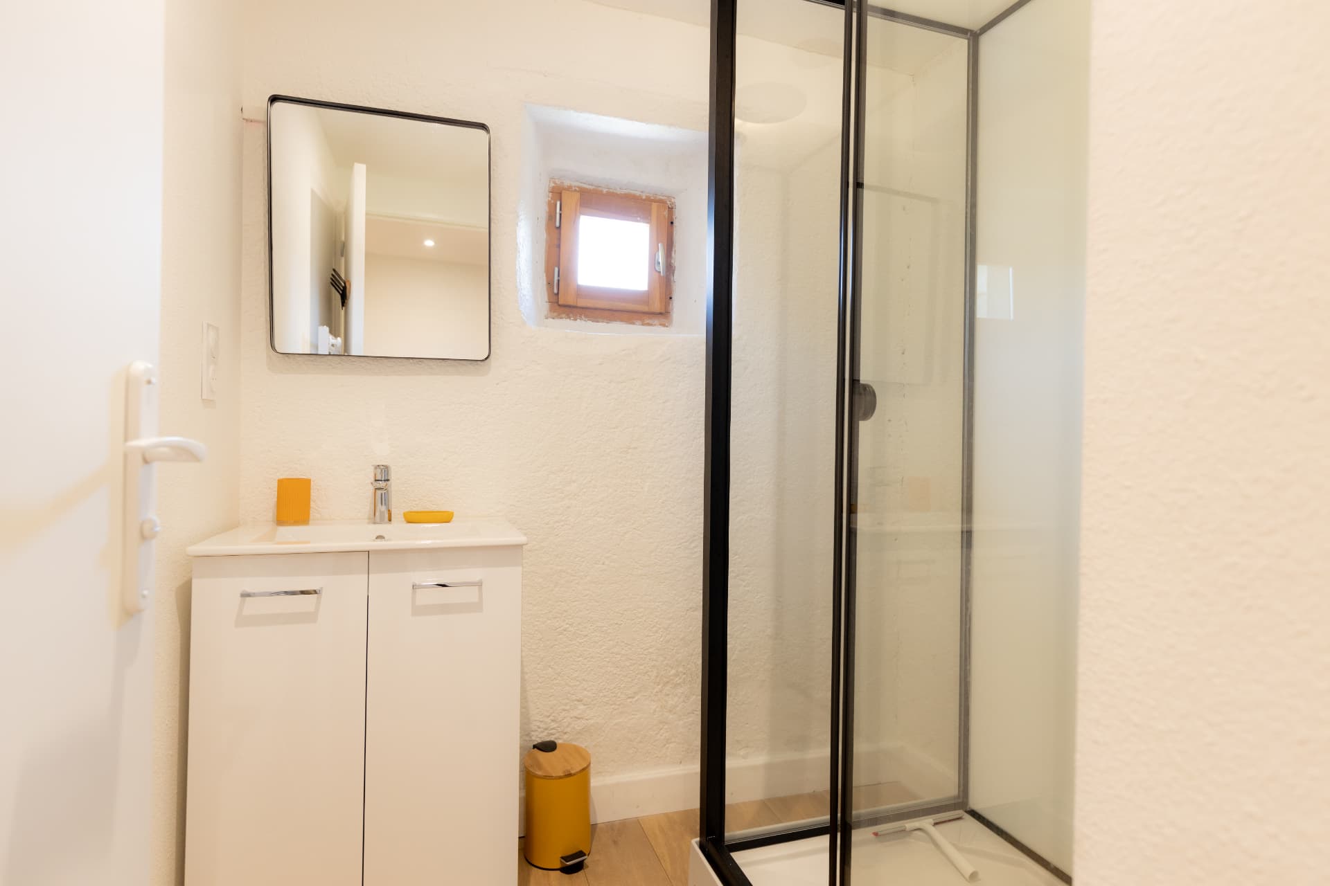 Salle de bain lumineuse avec douche et petite fenêtre