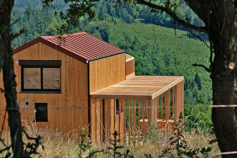 COQhome en bois avec toit rouge sur son plateau face à la forêt